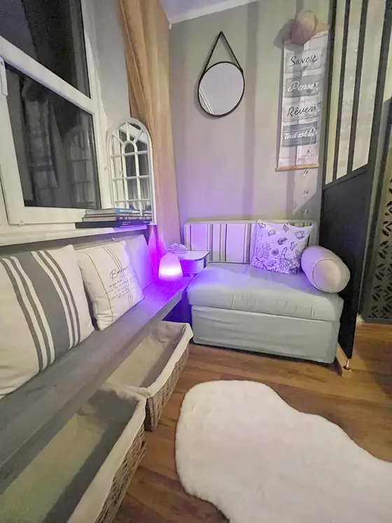Coin salon cosy avec banquette rayée et éclairage d'ambiance violet, vue sur le port